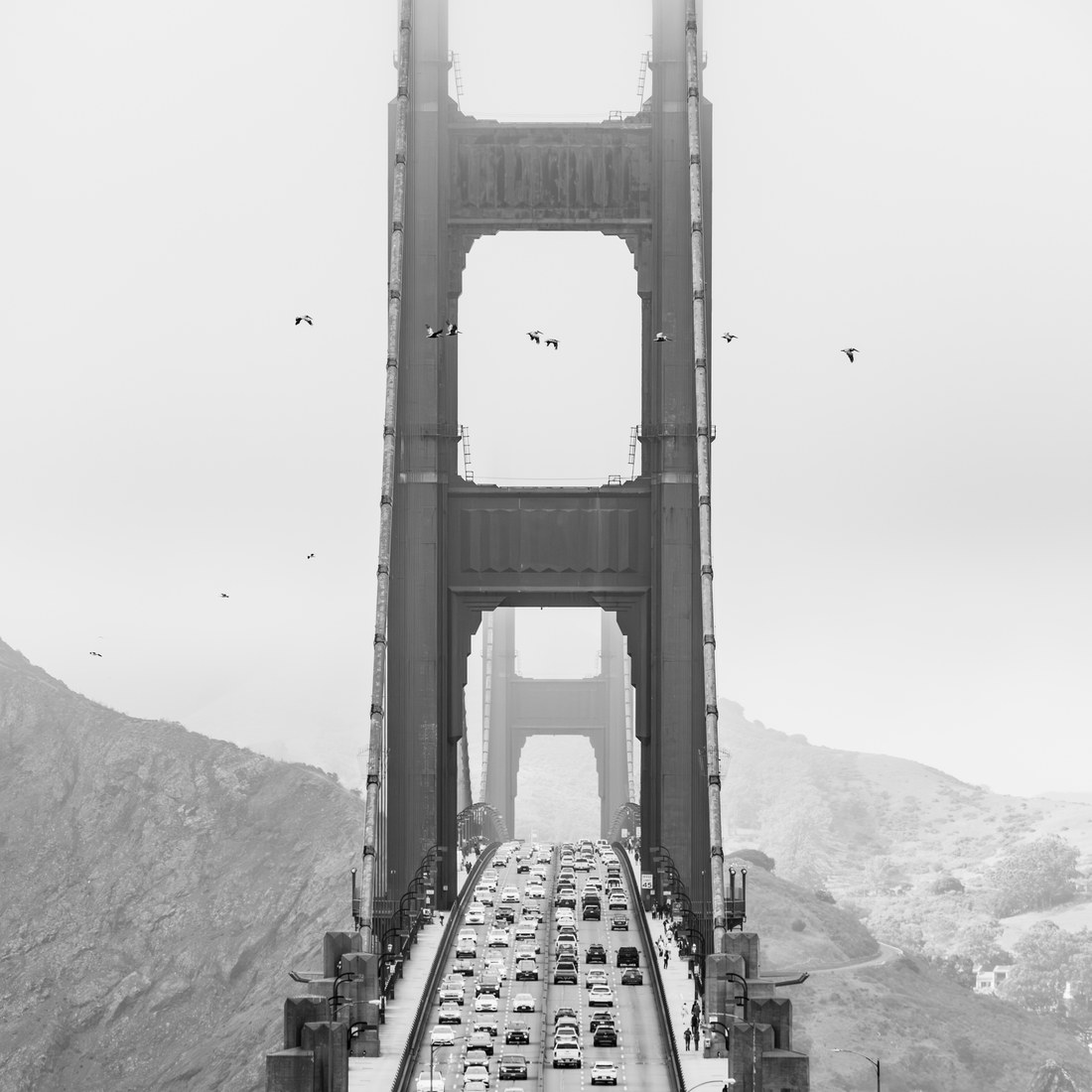 The Golden Gate Bridge tower disappearing into fog, traffic on the deck below