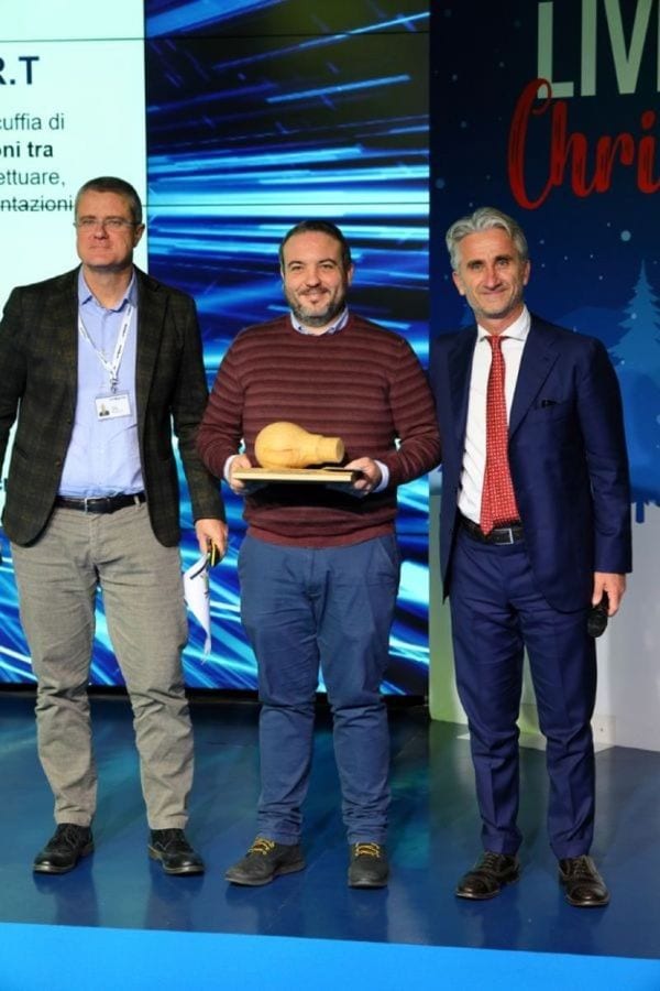 Denis Billi sul palco con il trofeo SCM Innovations Award, tra due dirigenti di SCM Group